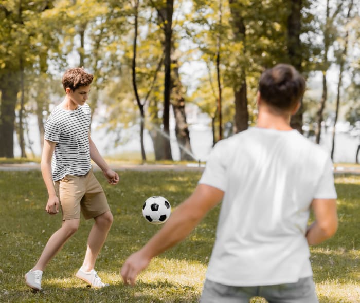 Two young men playing soccer in a park.