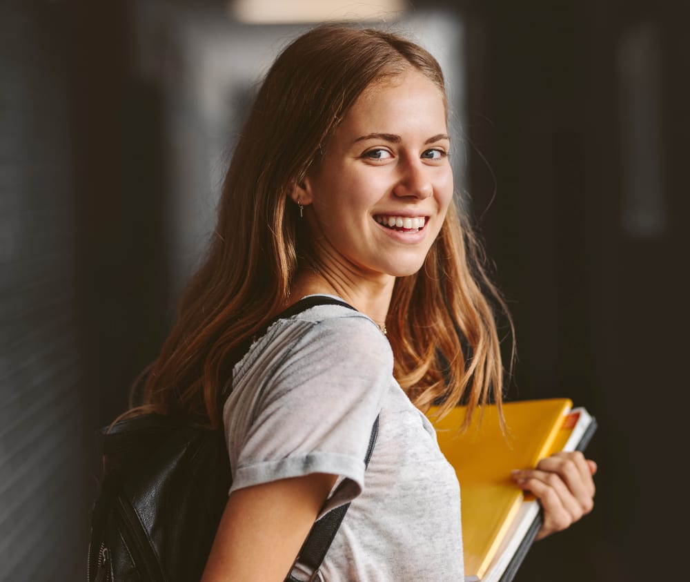 Teenaged girl with straight teeth smiling as she looks over her shoulder into the camera.