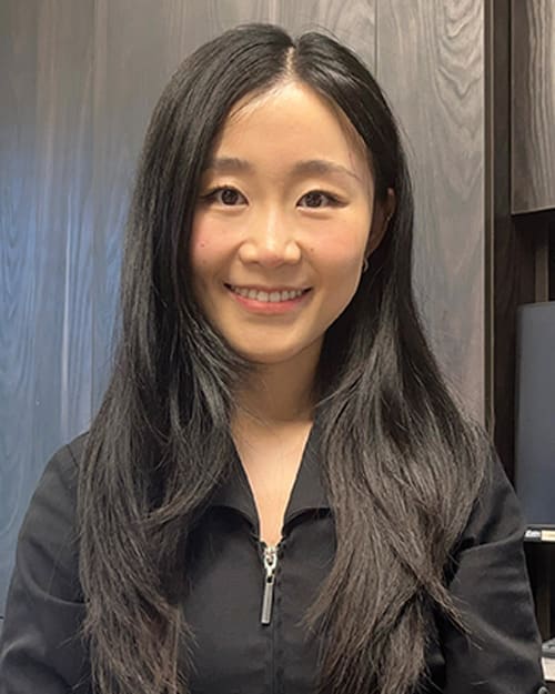 Portrait of our dentist Dr. Cindy Wei wearing a back shirt and smiling into the camera. smiling.